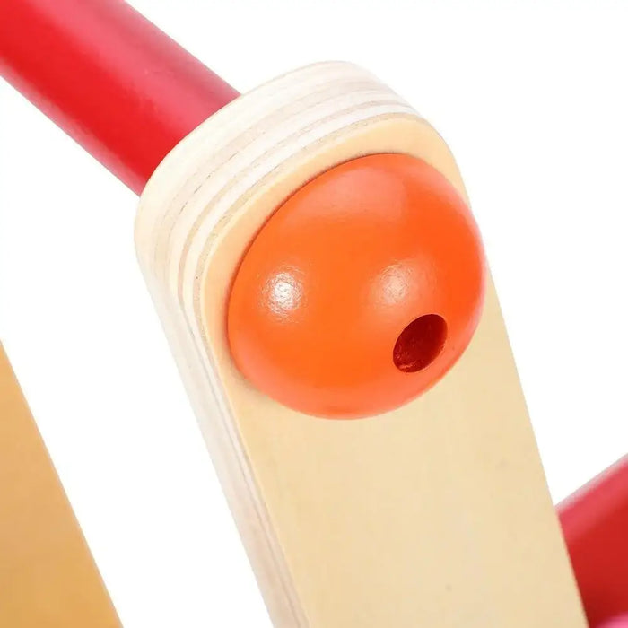Close-up of wooden baby walker with red handle and orange joint fitting
