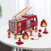 Wooden fire engine toy truck playset with ladder, four firefighter figurines, cones, and flames on a white table.