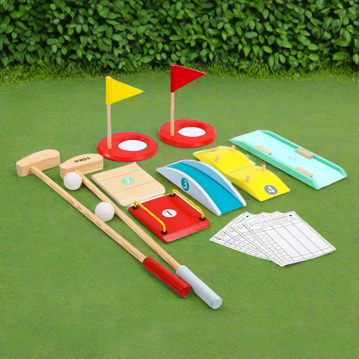 Wooden kids mini golf set with clubs, balls, colorful obstacles, and flags on green grass.