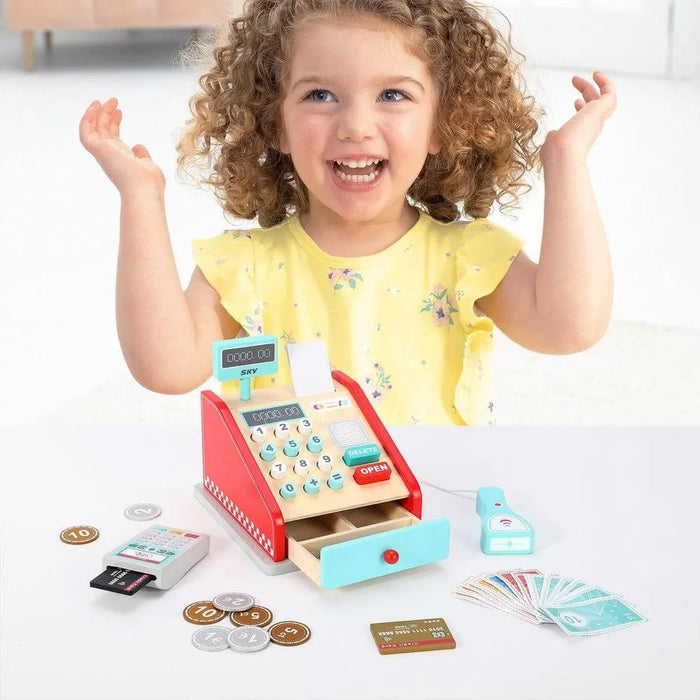 Smiling child playing with wooden kids cash register playset and pretend shop accessories