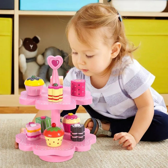 Toddler playing with pink wooden magnetic cake stand playset and wooden desserts