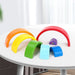 Wooden rainbow stacker toy with seven colorful arches on a white table